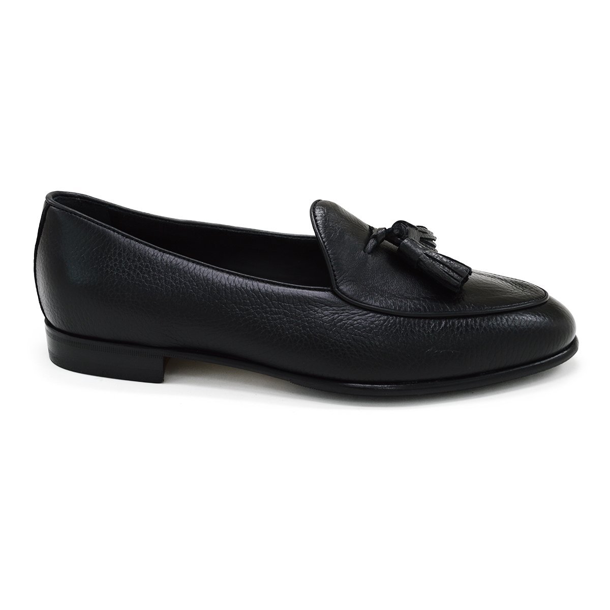 A black deerskin leather tassel Belgian loafer with an almond-shaped toe and a subtle tread sole, displayed against a white background.