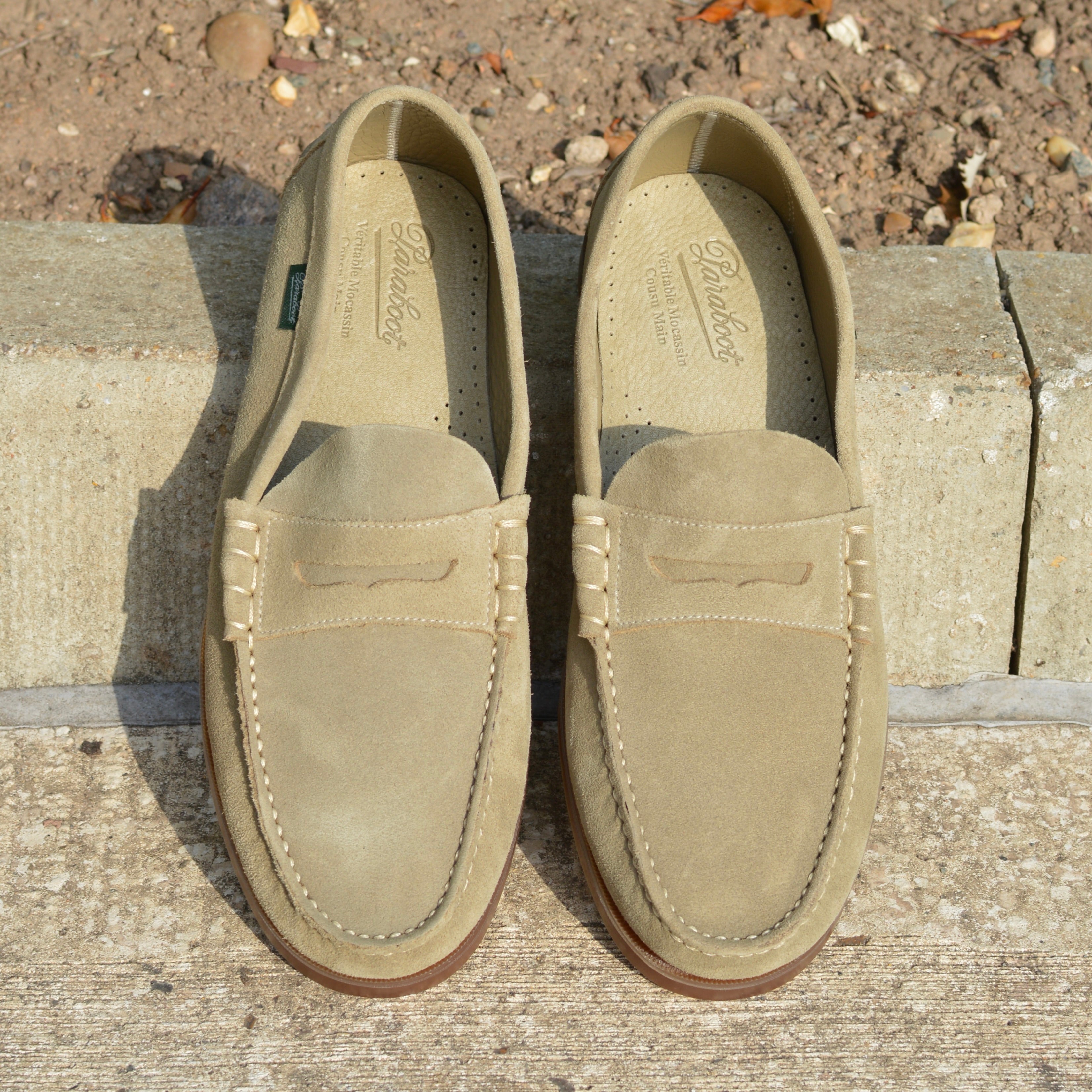 Pair of tan loafers on a stone surface