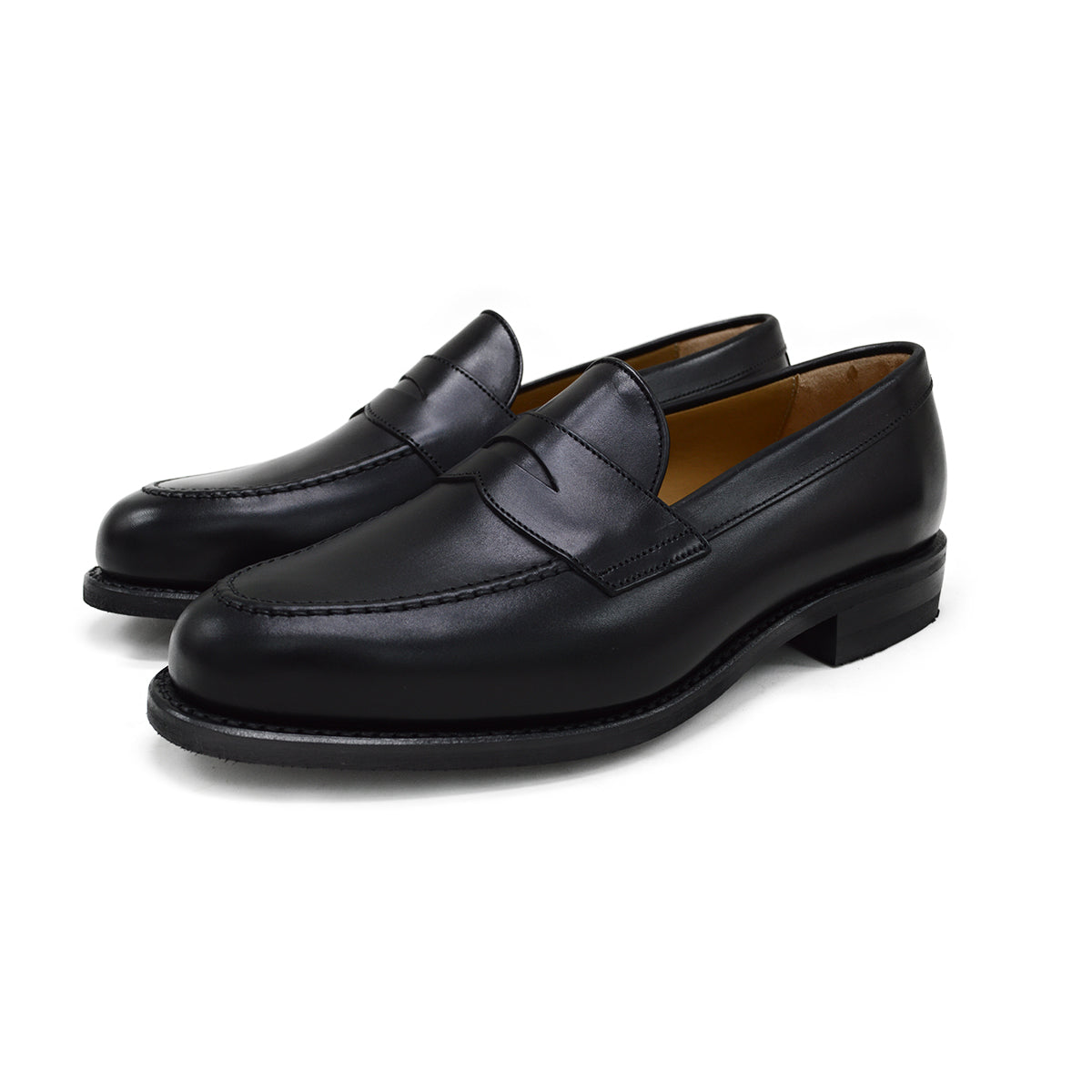 A black calf leather penny loafer with a Dainite rubber sole, showing a classic round toe shape and the iconic penny slot detail.