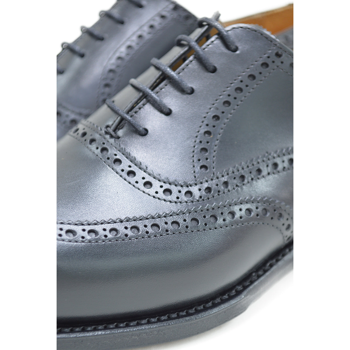 A Berwick 1707 black Oxford brogue shoe with brogue detailing and a lace-up closure. The shoe is made of smooth leather and appears to be sturdy and durable.
