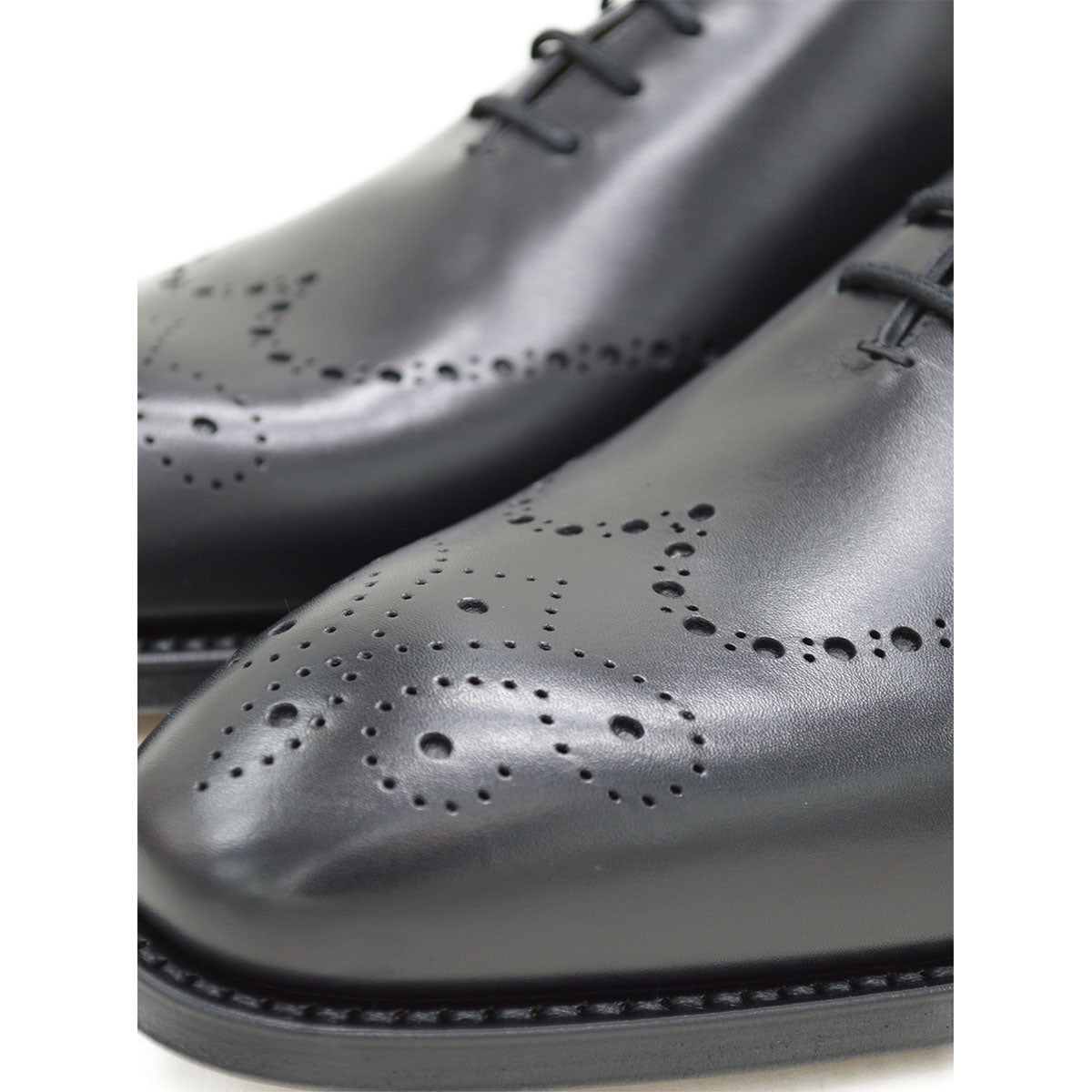 A black wholecut Oxford brogue shoe with a brogue pattern on the upper, a lace-up closure, and a goodyear welted leather sole.