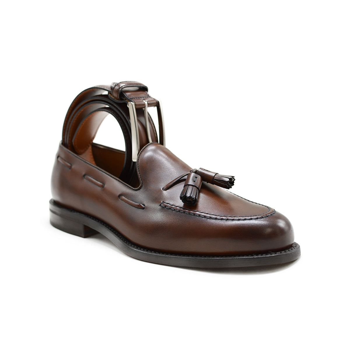 A Berwick 1707 brown calf leather belt with a silver chrome buckle, displayed on a white background with the same colour Berwick 1707 tasselled loafer