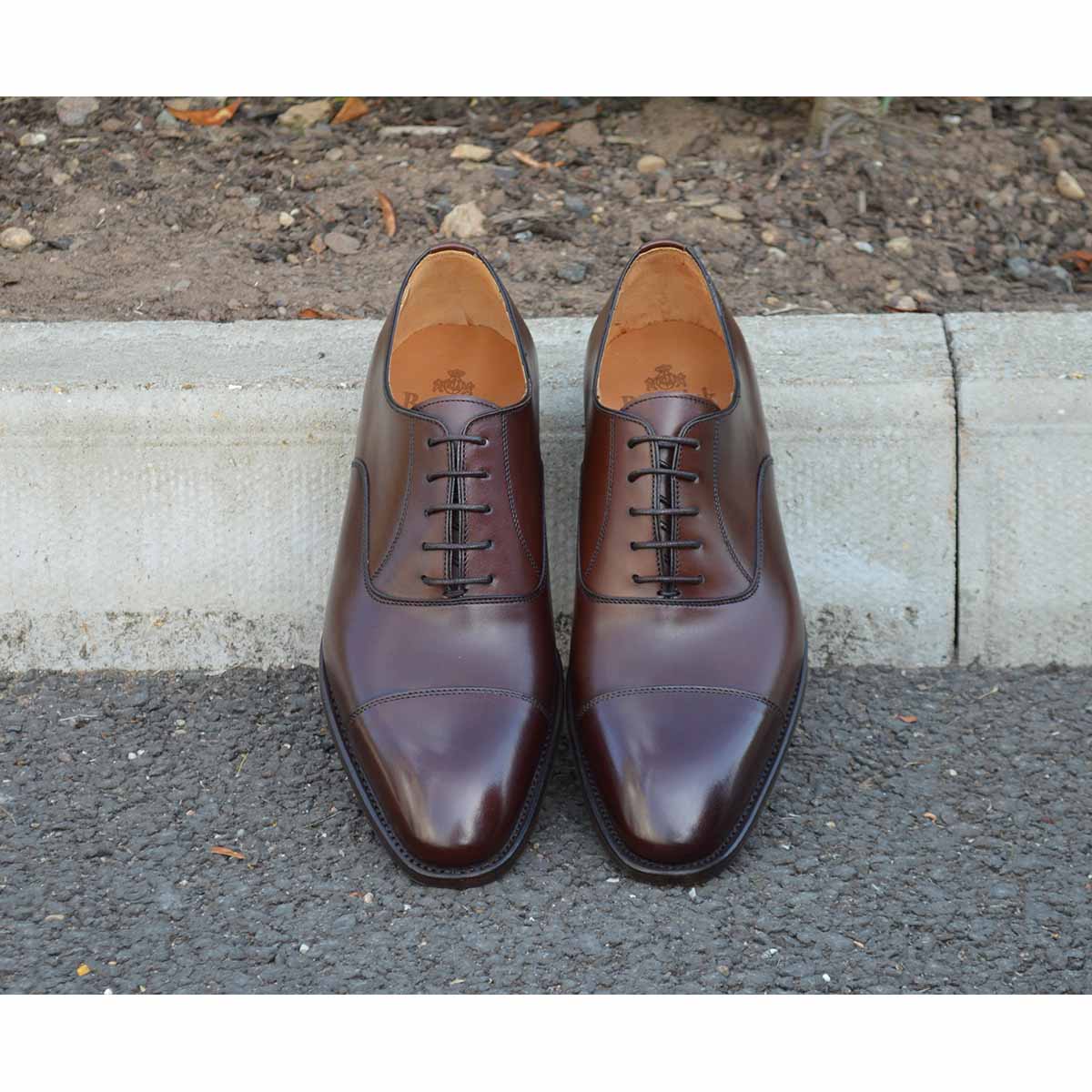 A Berwick 1707 dark brown, chisel toe Oxford shoe with a lace-up closure and a single leather sole.