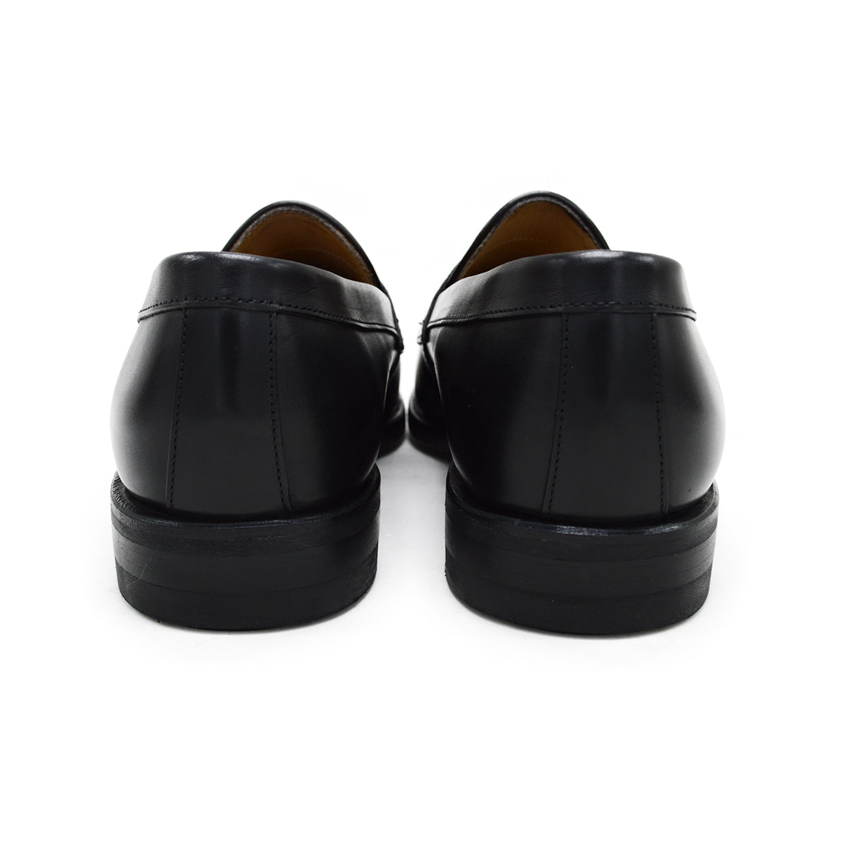 A black calf leather penny loafer with a Dainite rubber sole, showing a classic round toe shape and the iconic penny slot detail.