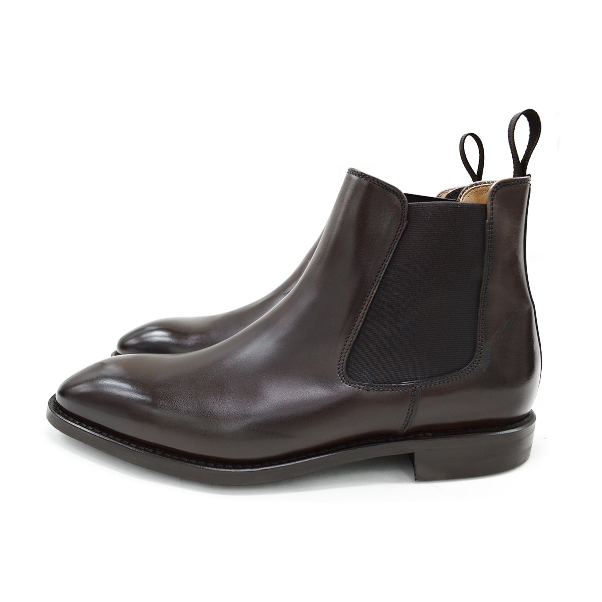 A dark brown leather Chelsea boot with a side pull tab and a low heel & Dainite soles, displayed on a white background.