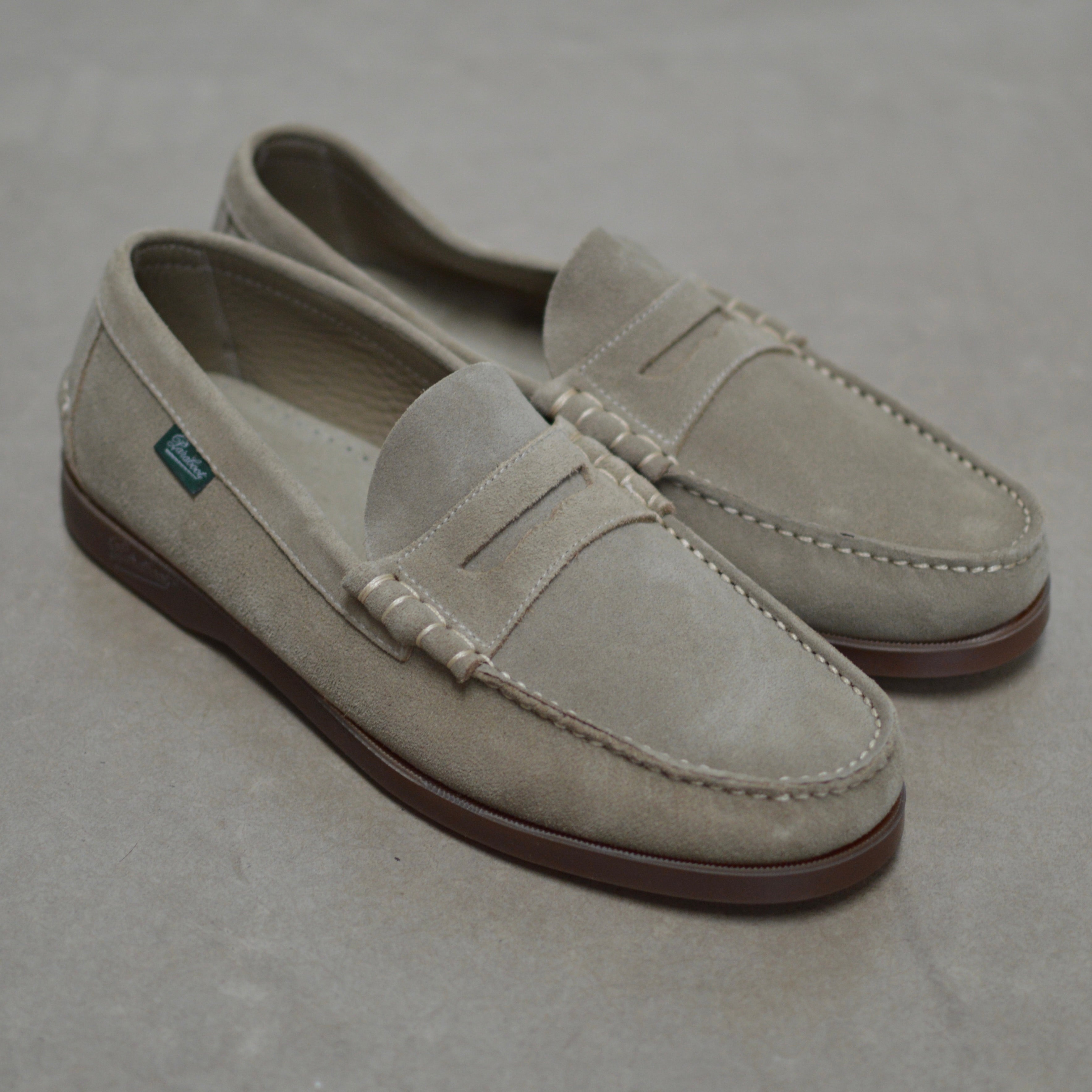 Pair of beige loafers on a gray background