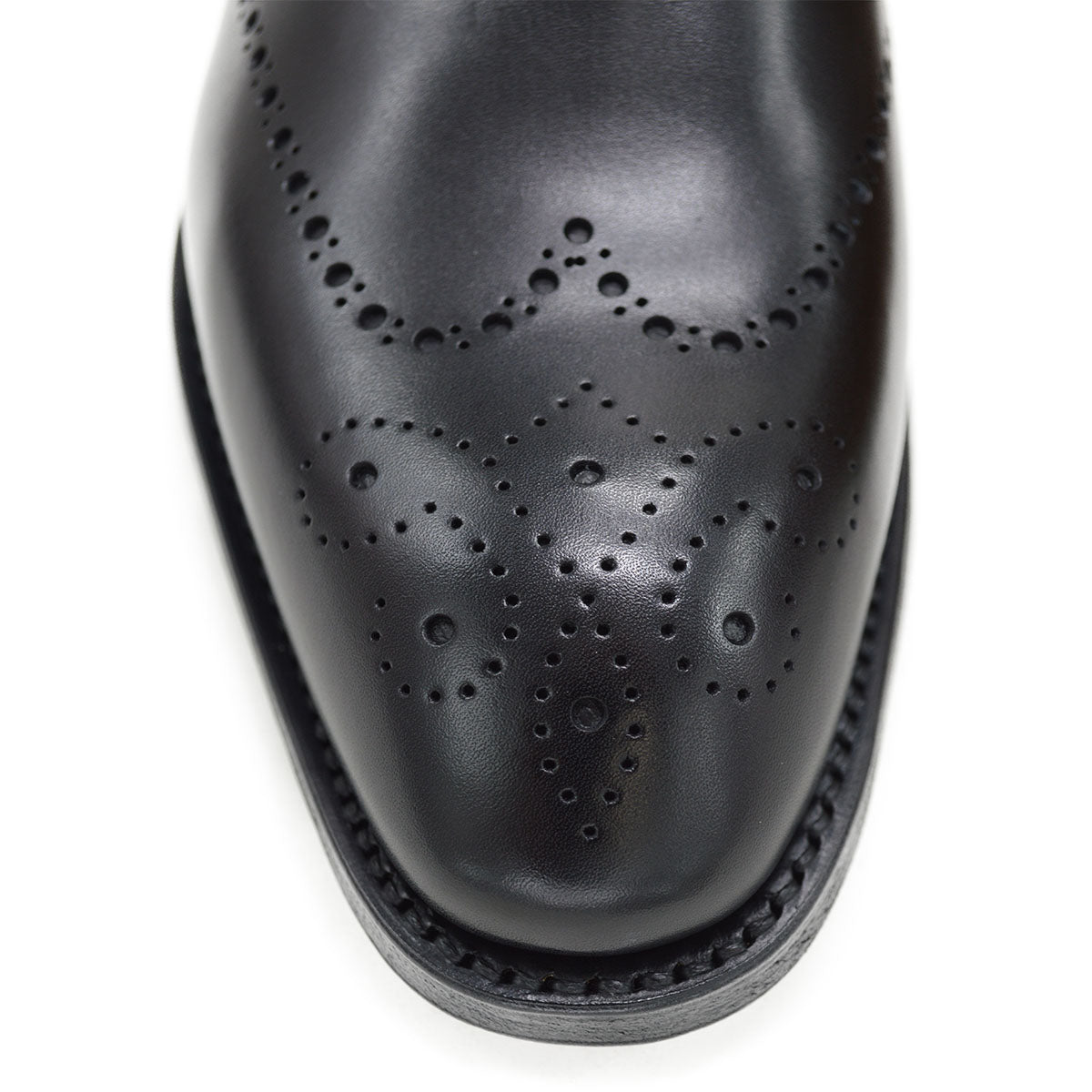 A black wholecut Oxford brogue shoe with a brogue pattern on the upper, a lace-up closure, and a goodyear welted leather sole.
