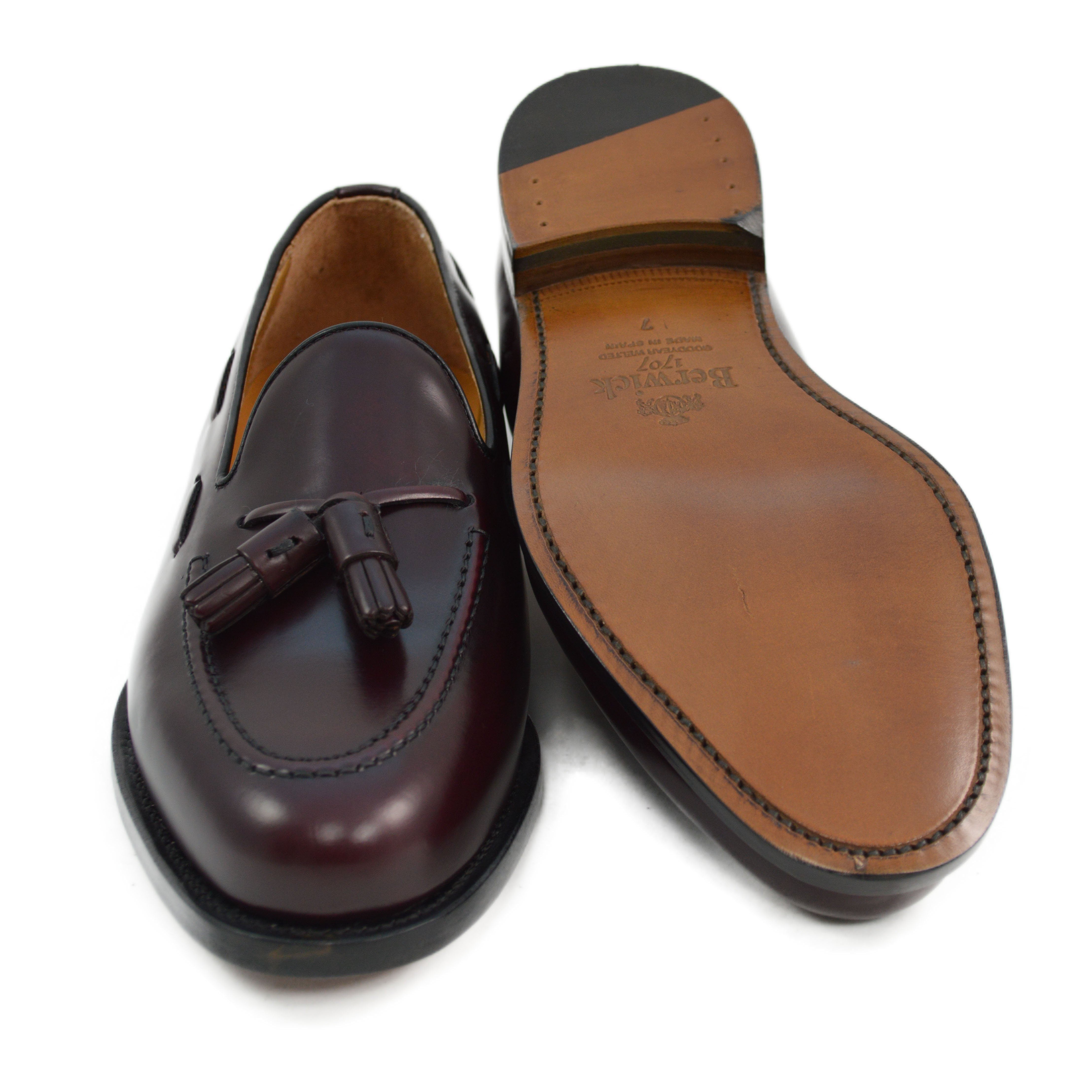 A Berwick 1707 burgundy hi shine leather slip-on shoe with a tassel detail on the vamp, set against a white background.