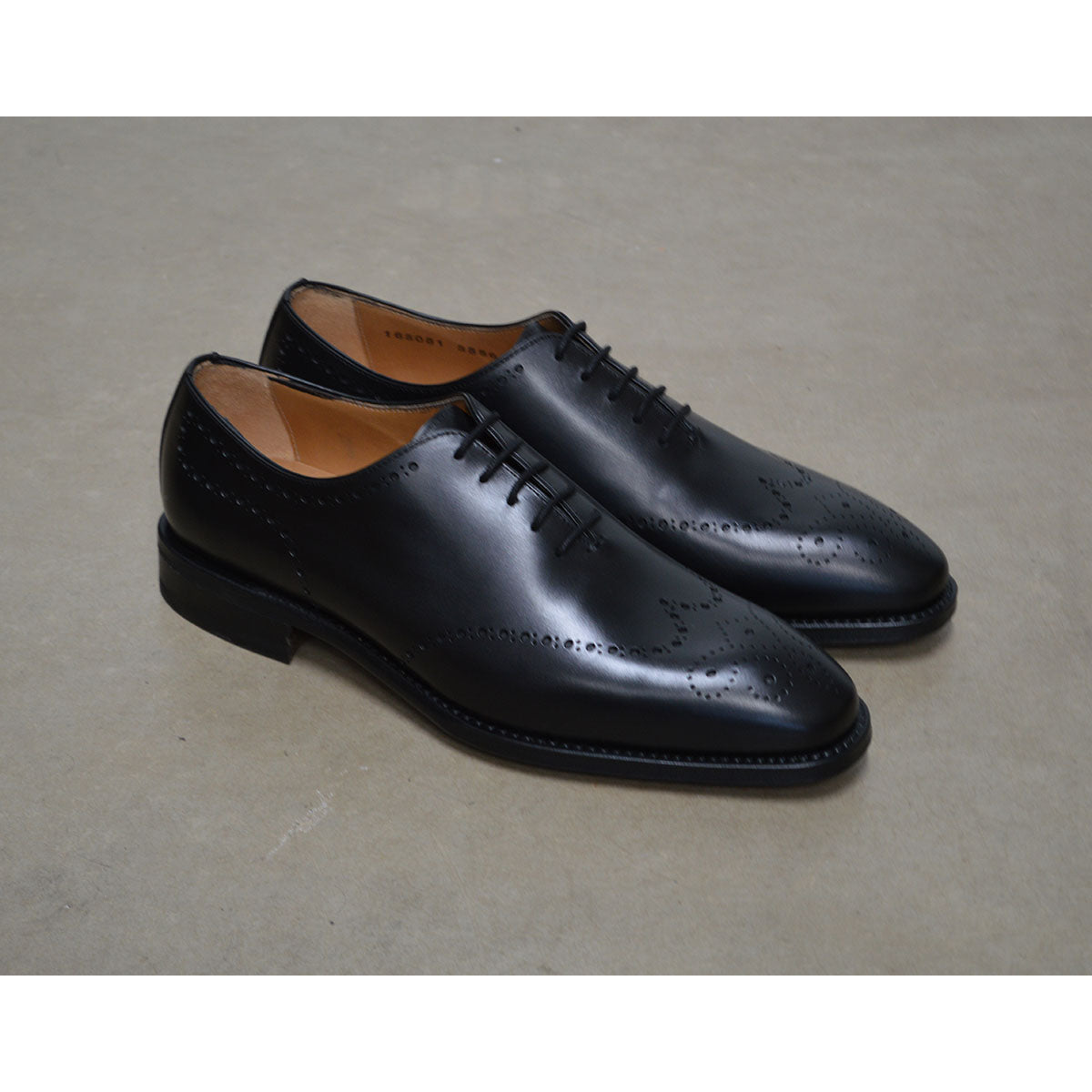 A black wholecut Oxford brogue shoe with a brogue pattern on the upper, a lace-up closure, and a goodyear welted leather sole.