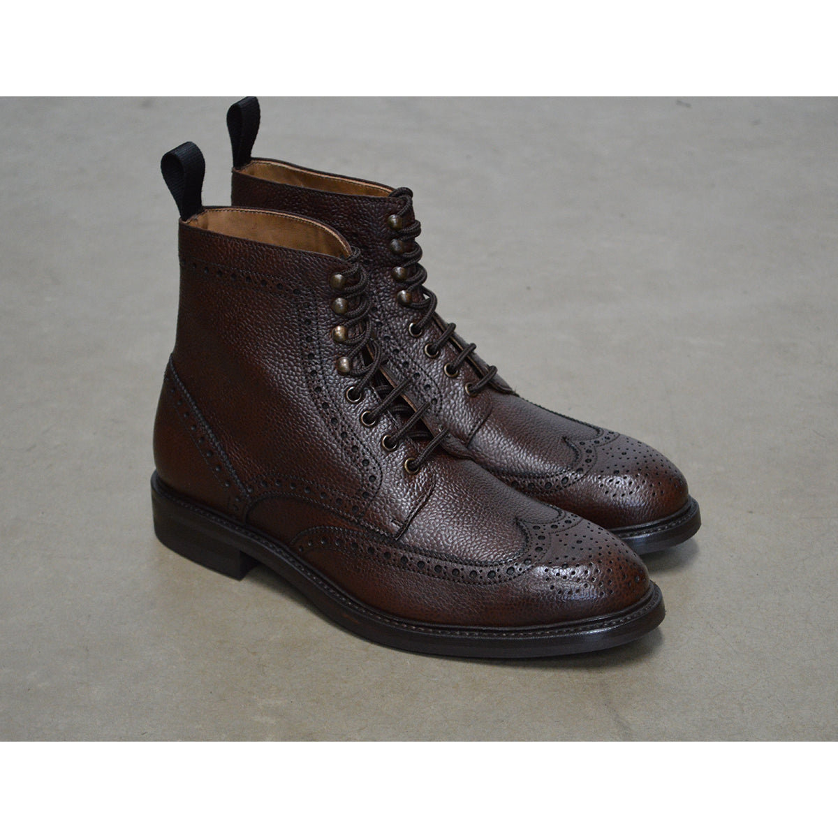 A Berwick 1707 dark brown brogue boot with a lace-up closure, round toe shape, and a Dainite rubber sole.