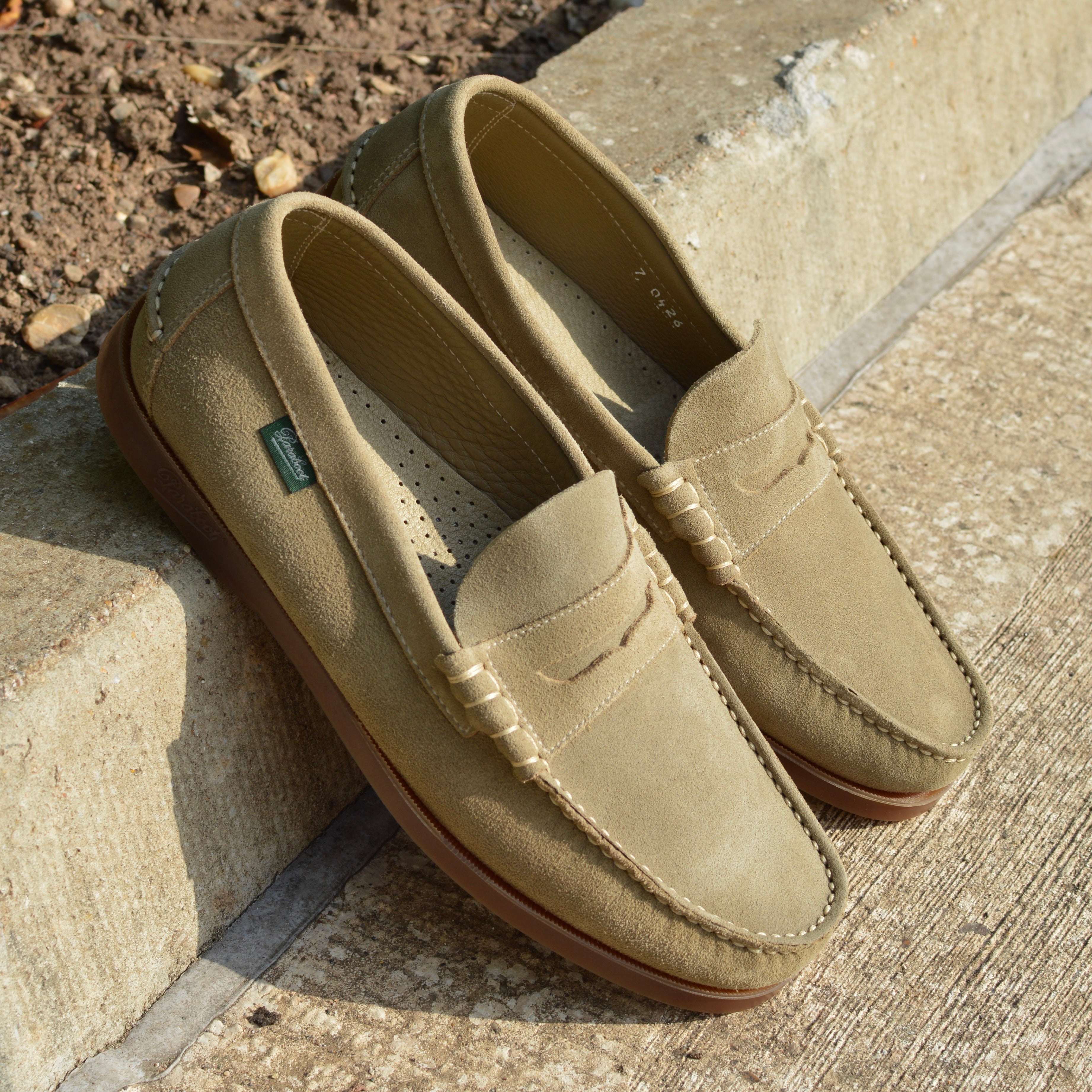 Pair of beige loafers on a stone surface