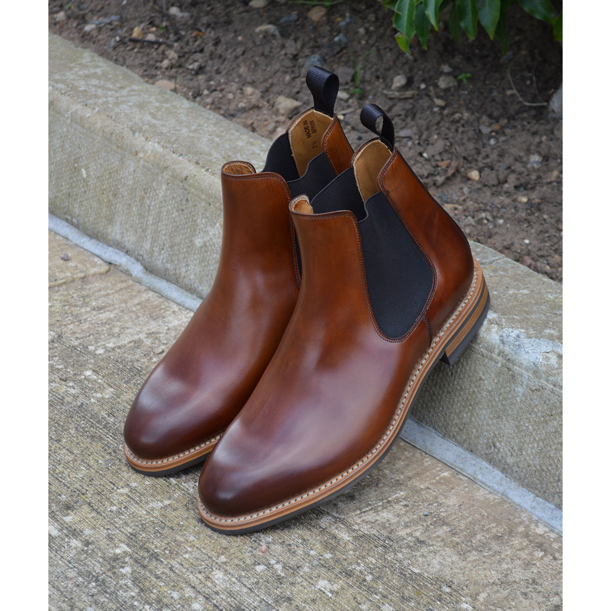 A brown Berwick 1707 Chelsea Boot with a pull tab on the side, showcasing a traditional round-toe shape and a natural welt with a Dainite rubber sole.