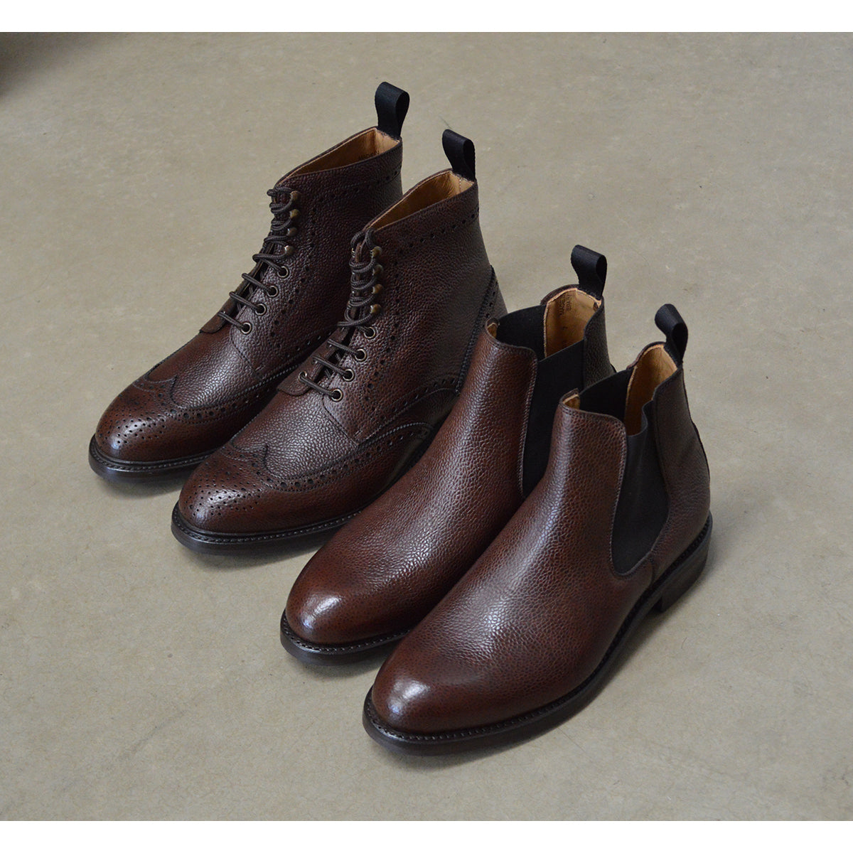 A dark brown grain leather Chelsea boot with a black elastic side panel and a round toe. The boot has a low heel and a goodyear welted dainite rubber sole.