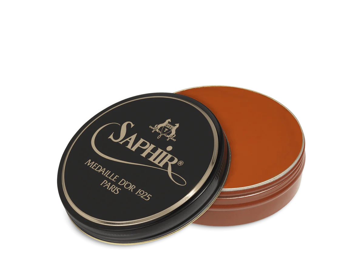 A round tin container of Saphir Medaille D'Or shoe wax polish with black lid and gold lettering.