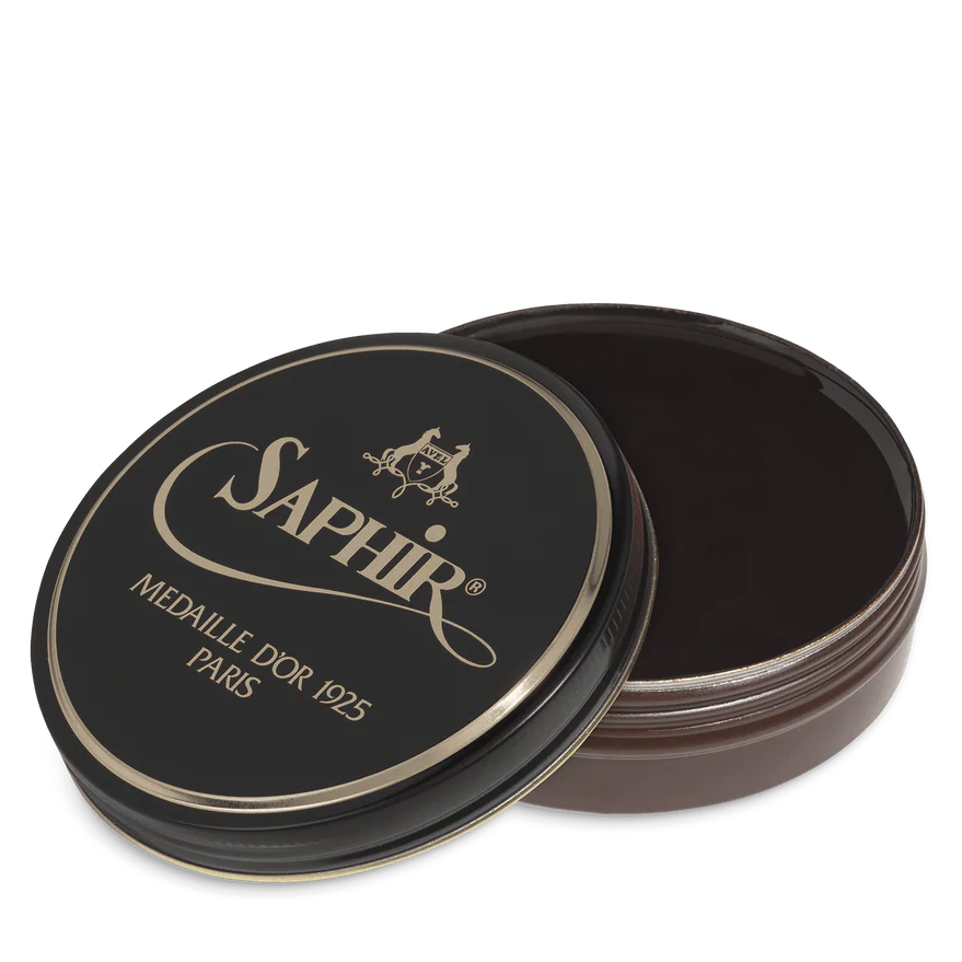 A round tin container of Saphir Medaille D'Or shoe wax polish with black lid and gold lettering.