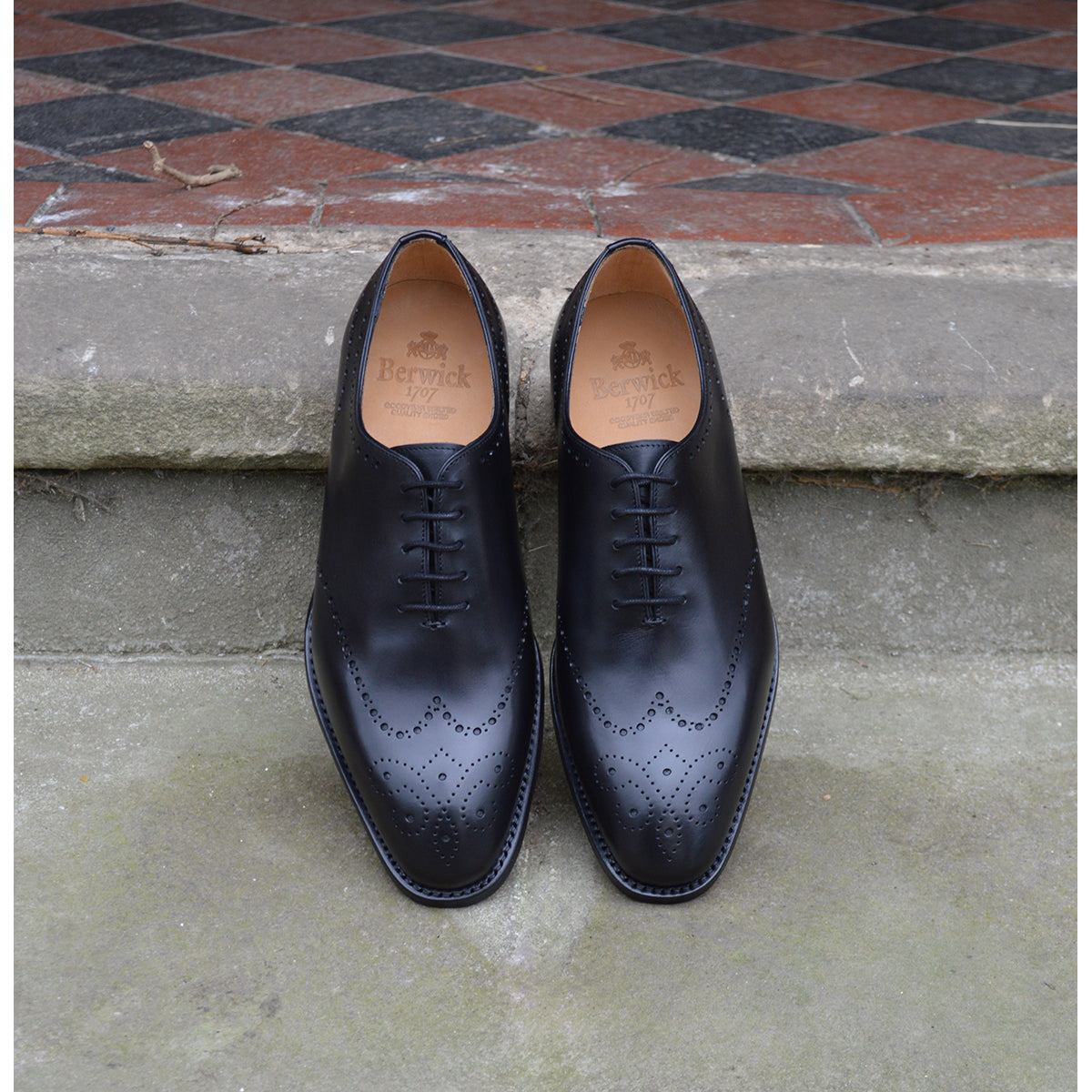 A black wholecut Oxford brogue shoe with a brogue pattern on the upper, a lace-up closure, and a goodyear welted leather sole.