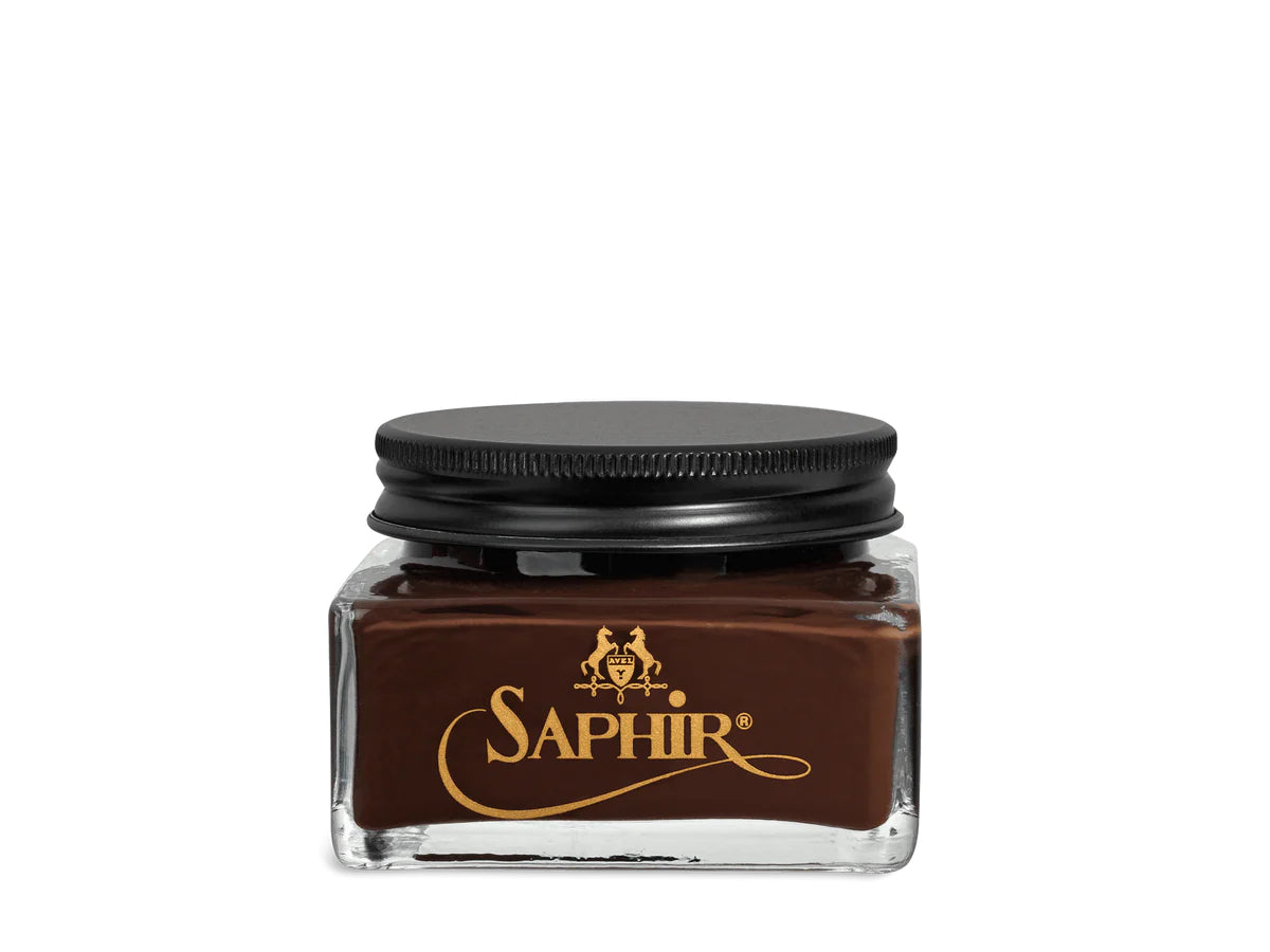A glass jar with a black lid labeled 'SAPHIR' containing cream shoe polish.