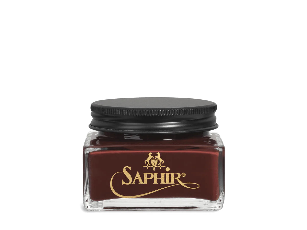 A glass jar with a black lid labeled 'SAPHIR' containing cream shoe polish.