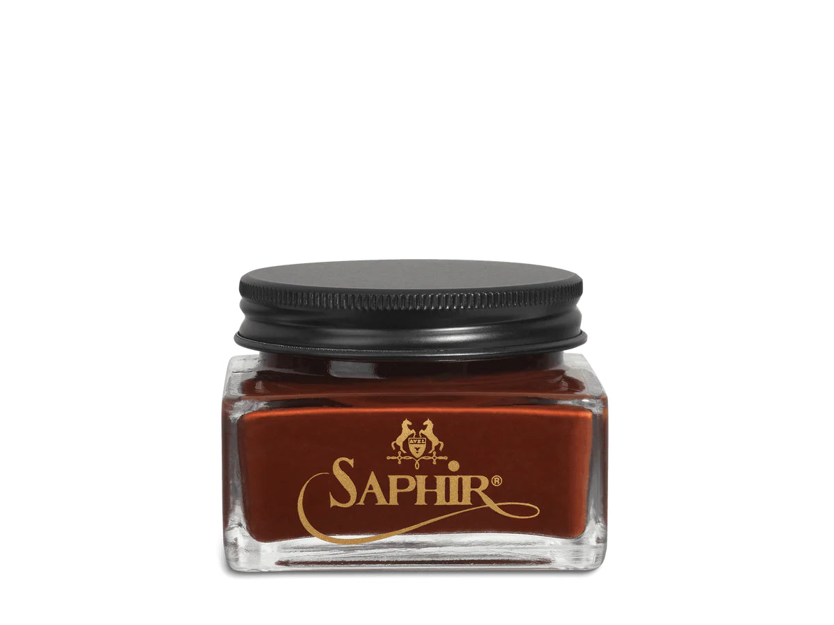 A glass jar with a black lid labeled 'SAPHIR' containing cream shoe polish.