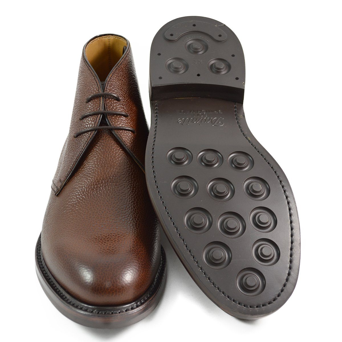 A dark brown grain leather chukka boot with a round toe and goodyear welted dainite rubber sole.