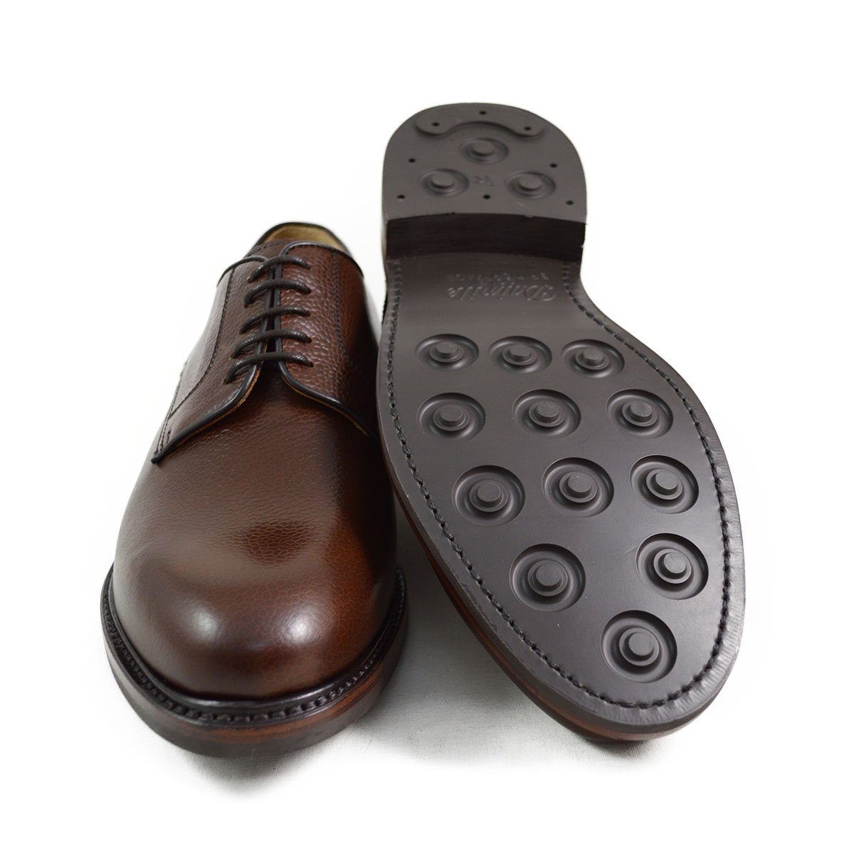 A dark brown, grainy-textured leather derby shoe with a round toe and classic lace-up closure & Dainite soles