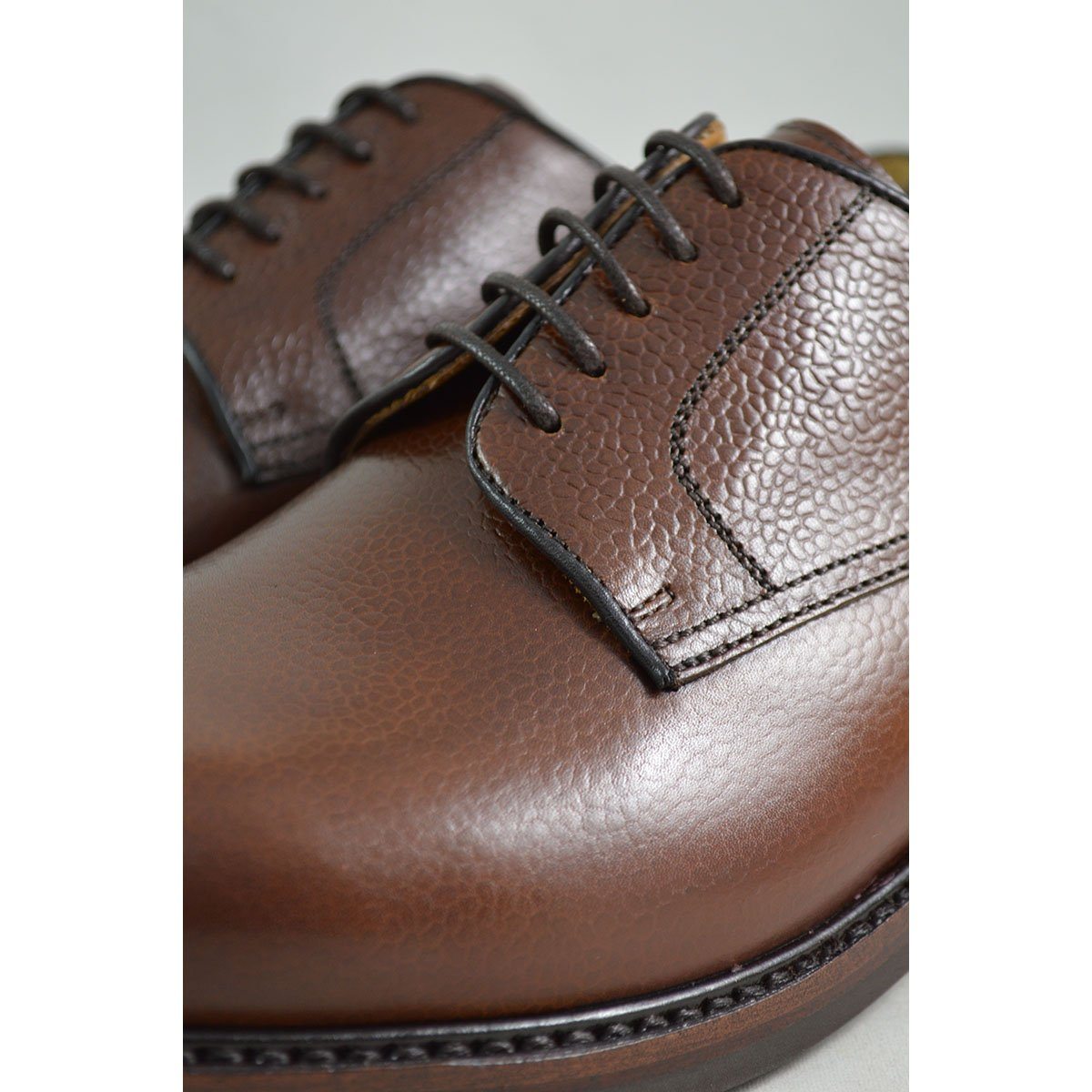 A dark brown, grainy-textured leather derby shoe with a round toe and classic lace-up closure & Dainite soles