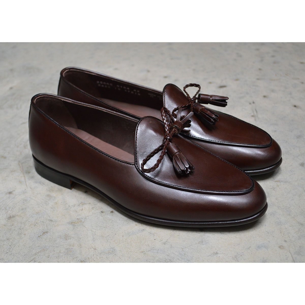 A Berwick 1 707 dark brown leather Belgian loafer with a braided leather bow tie and tassel adornment.