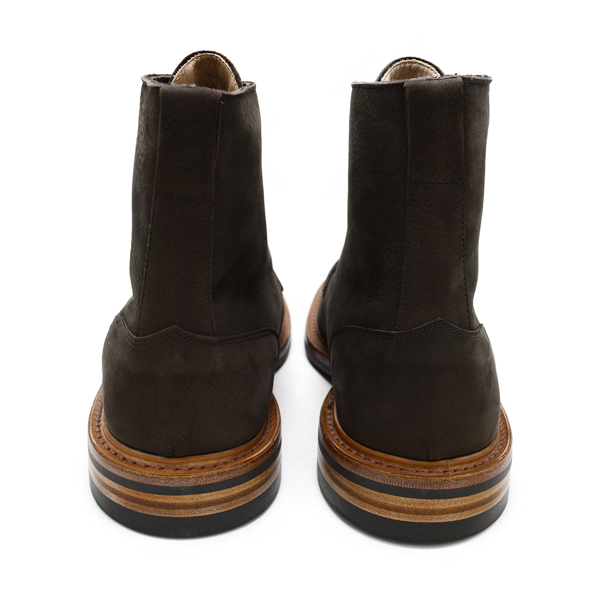 A dark brown Trickers Bernwood service boot made of Hydro Nubuck with a Dainite sole, featuring brass eyelets and a cream Barbour welt.