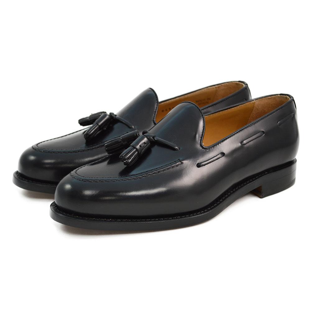 A black tasselled slip-on shoe with a high shine finish and a classic round toe.