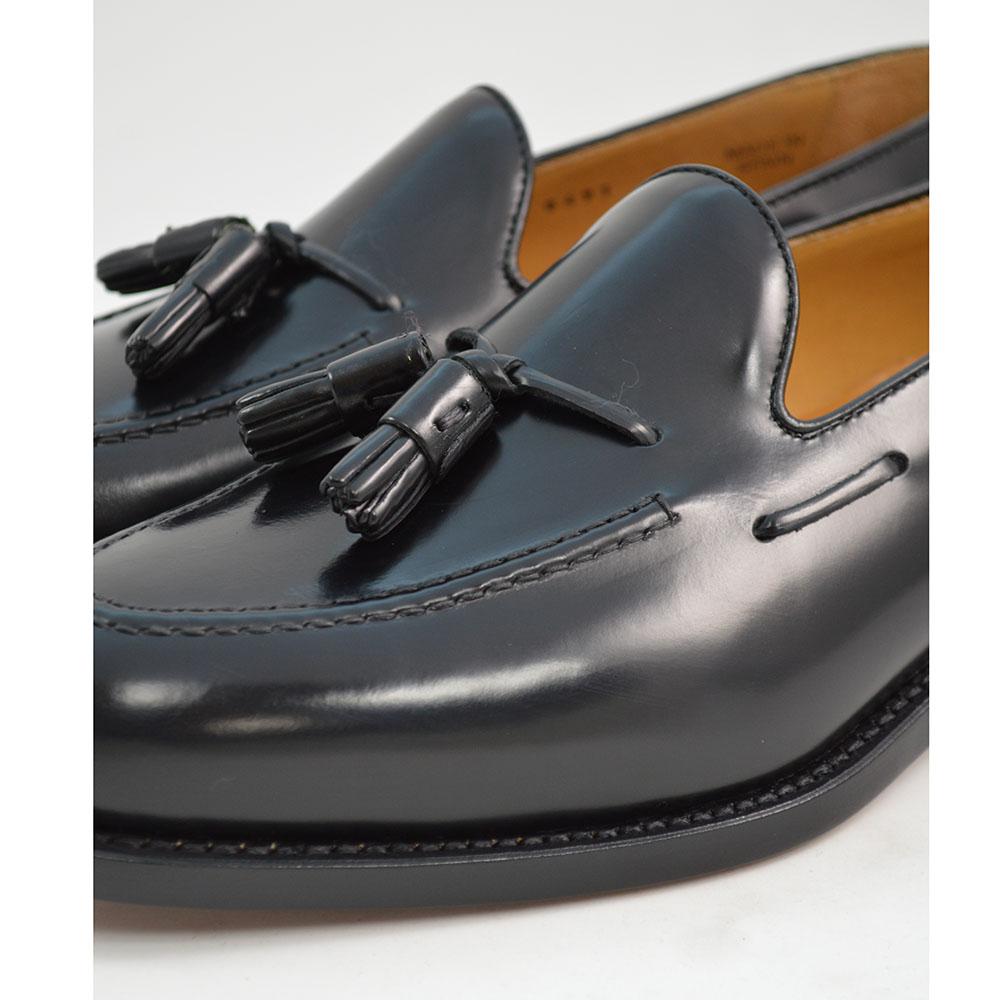 A black tasselled slip-on shoe with a high shine finish and a classic round toe.