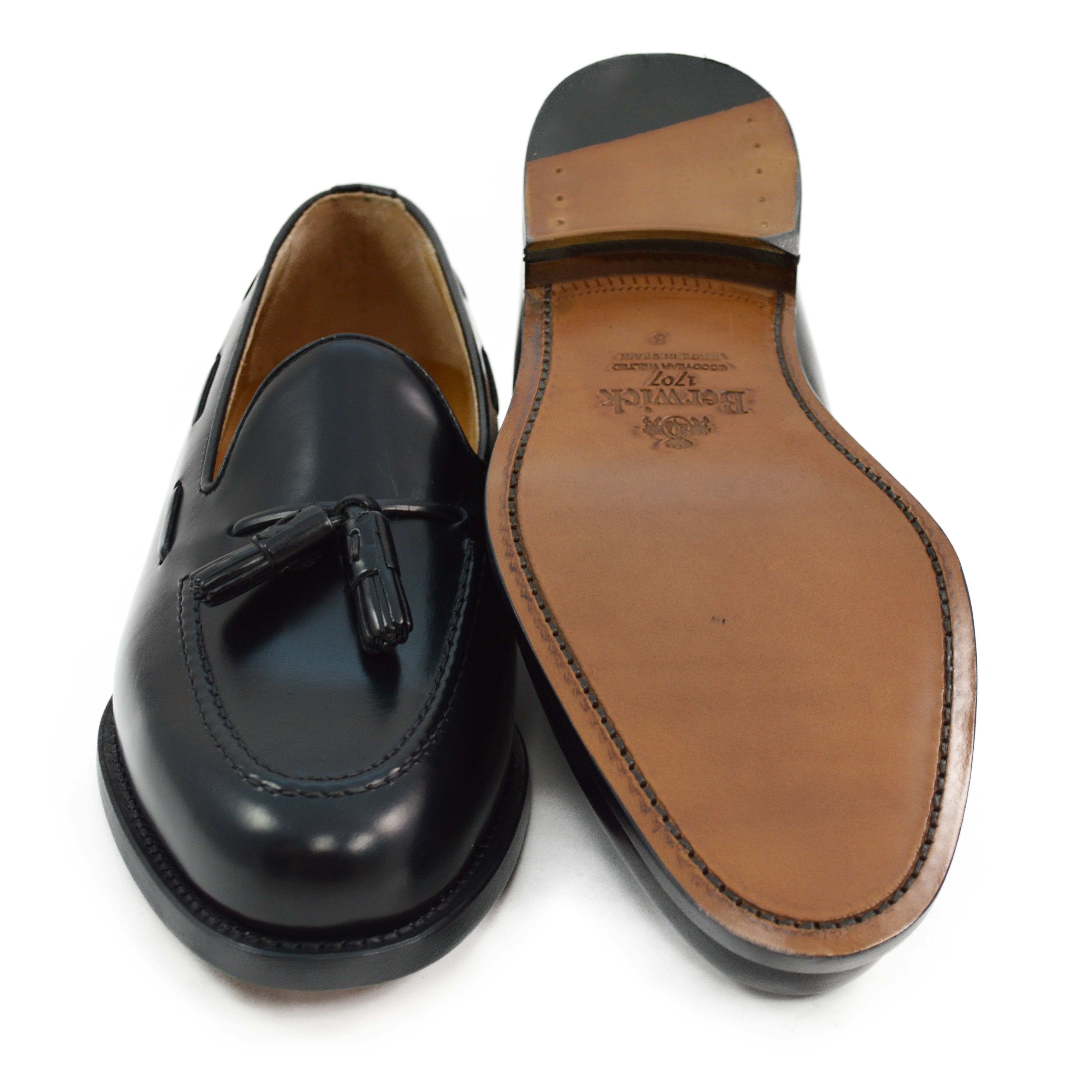 A black tasselled slip-on shoe with a high shine finish and a classic round toe.