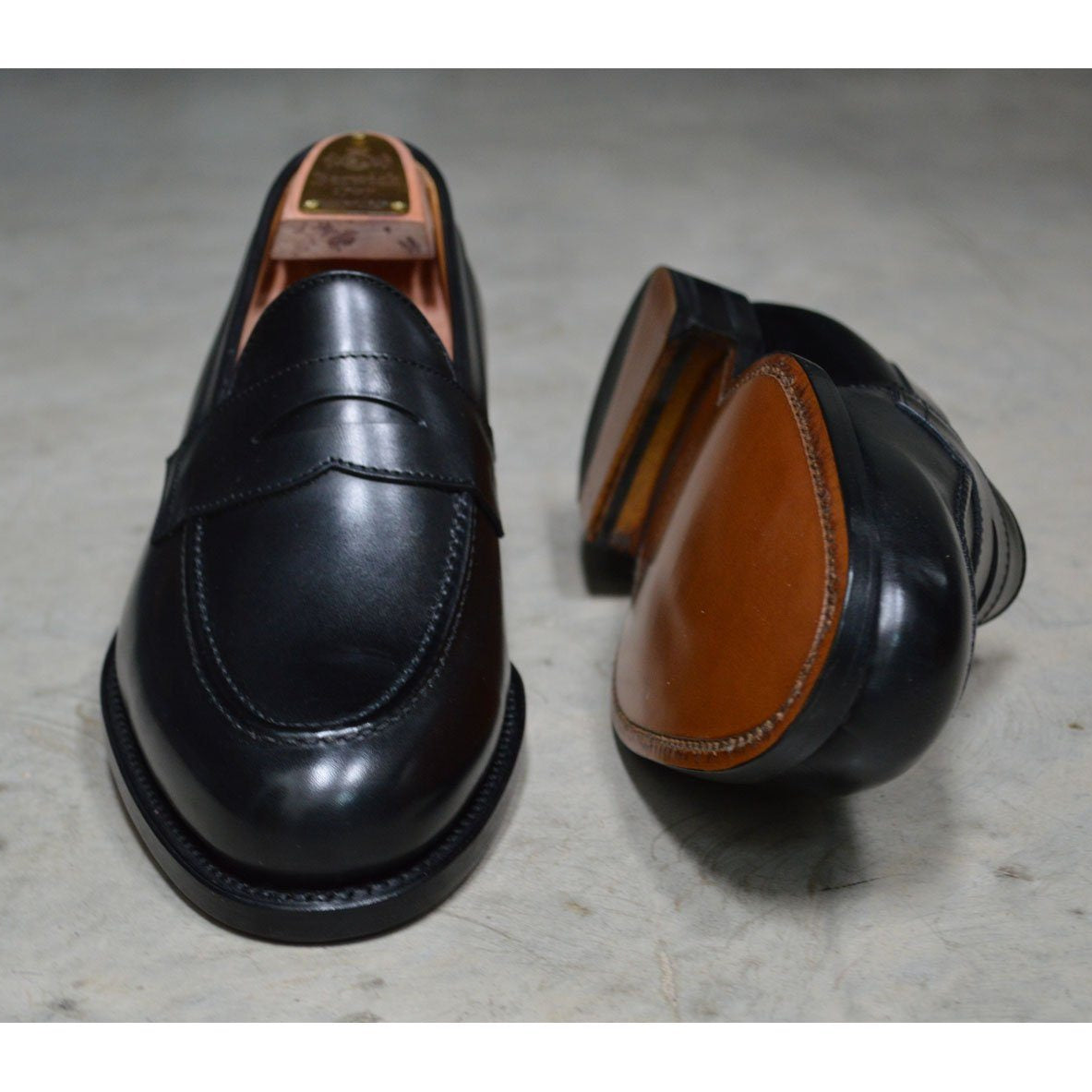A classic black leather penny loafer shoe for men, with a closed vamp and a low heel.