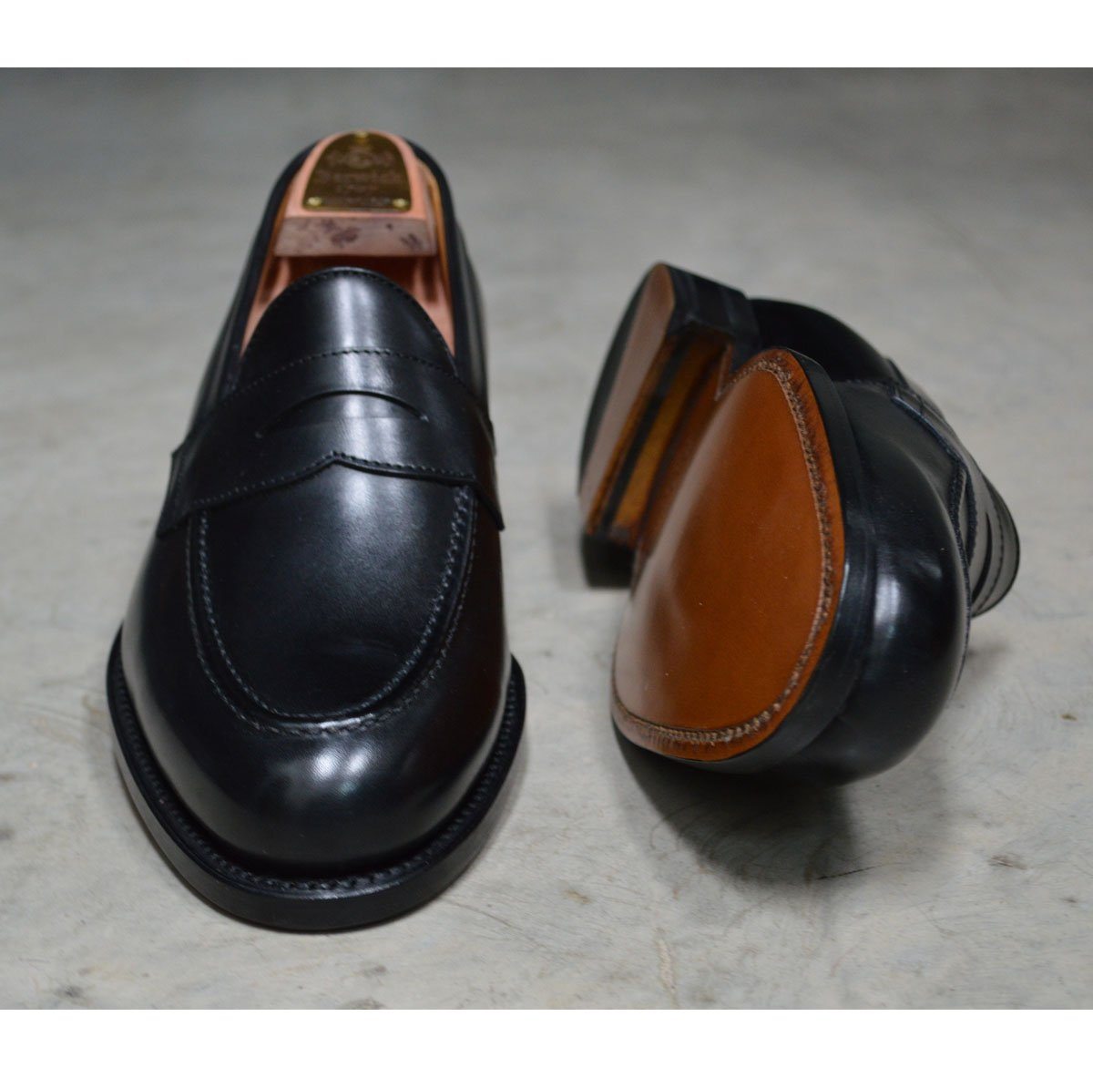 A classic black leather penny loafer shoe for men, with a closed vamp and a low heel.