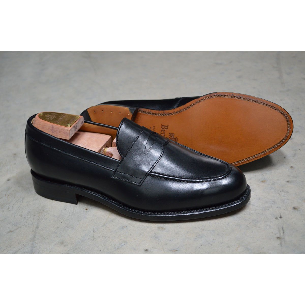 A classic black leather penny loafer shoe for men, with a closed vamp and a low heel.