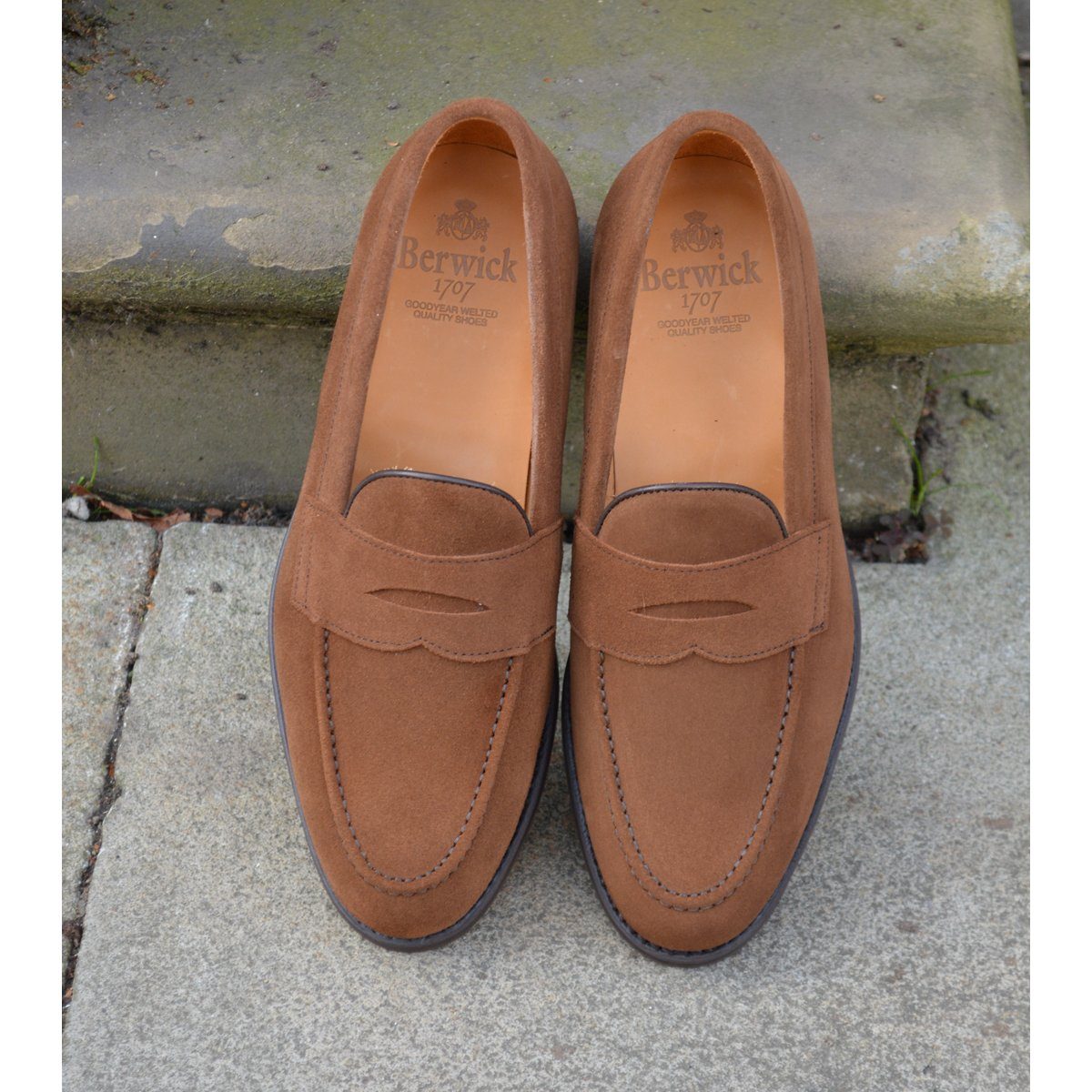 A brown suede penny loafer with a Dainite rubber sole, showing a classic round toe shape and a signature penny slot detail & Dainite Soles