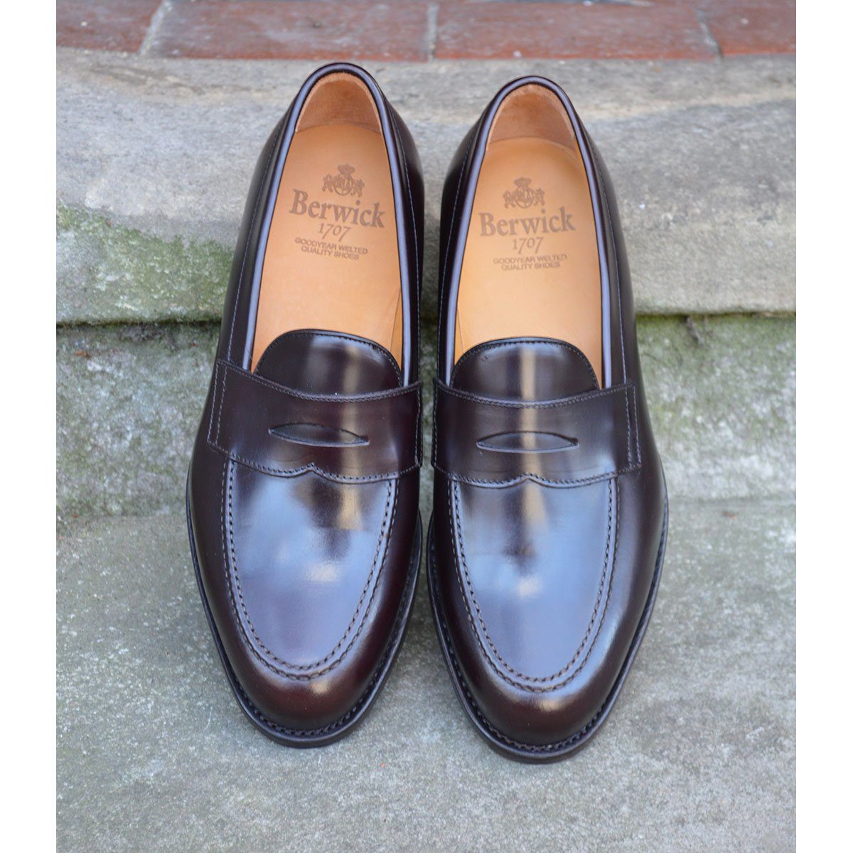 A dark brown Berwick 1707 Penny Loafer with a high-shine finish and a Dainite rubber sole.