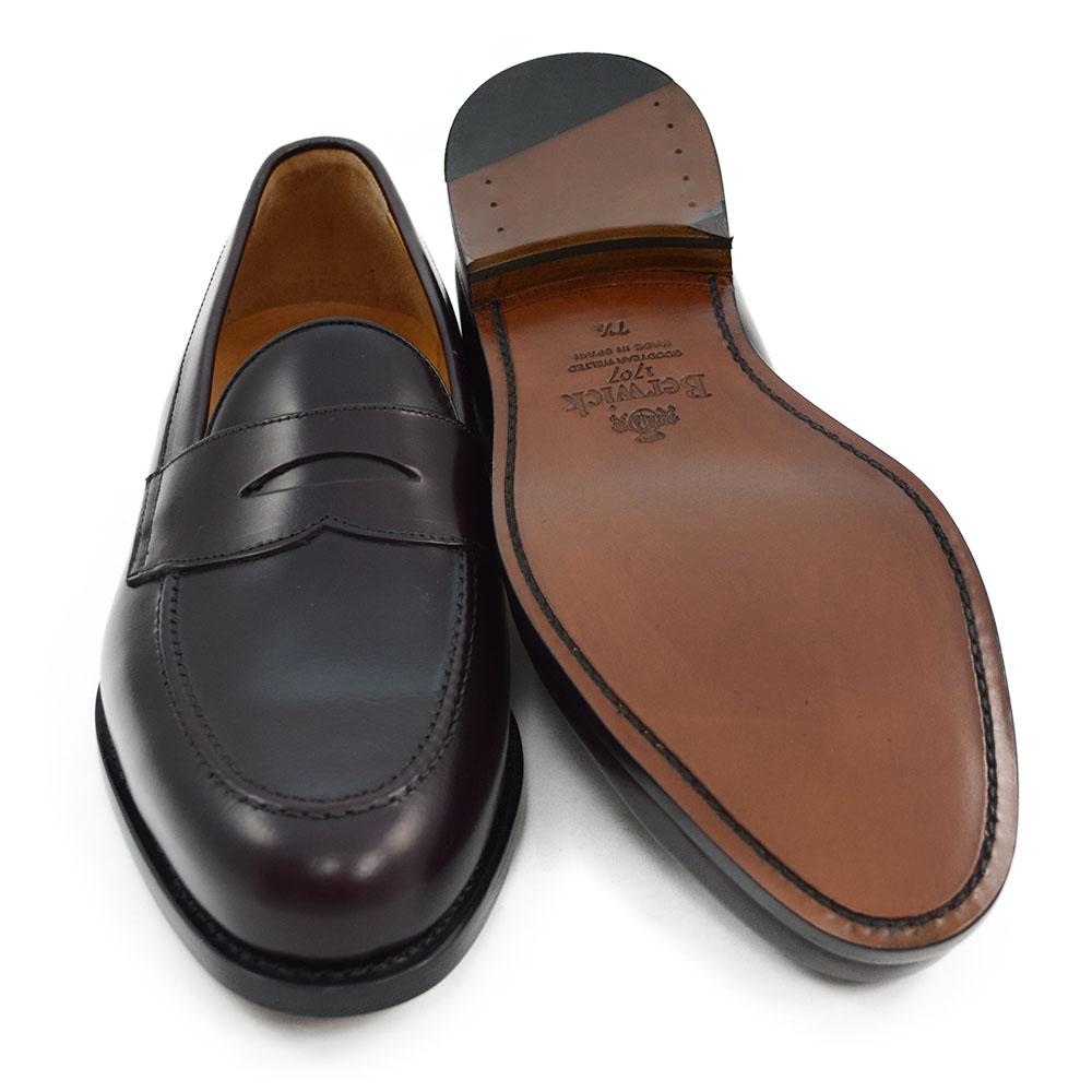 A burgundy high-shine leather penny loafer by Berwick 1707, displaying the classic round toe shape and the brand's distinctive penny slot detail.