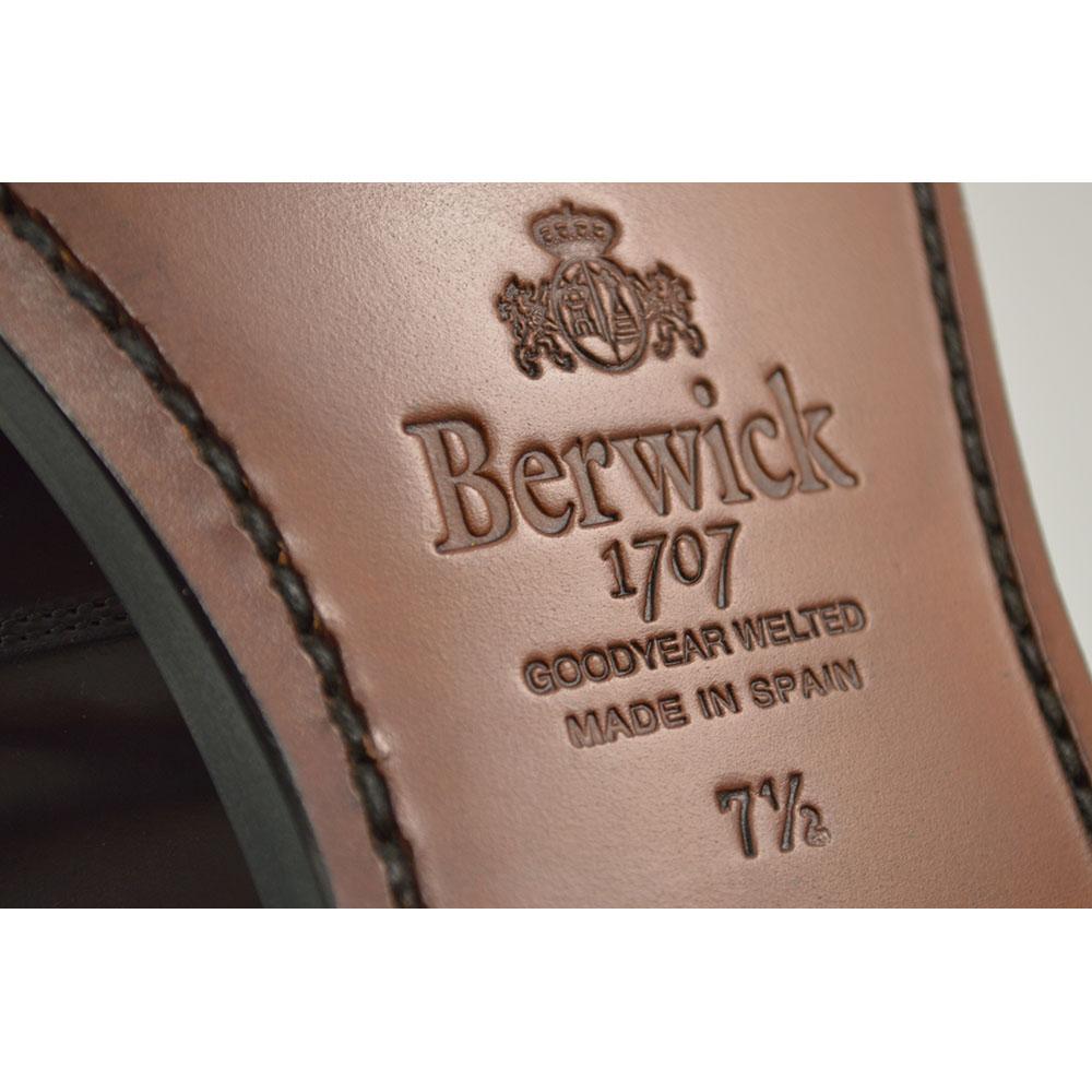A burgundy high-shine leather penny loafer by Berwick 1707, displaying the classic round toe shape and the brand's distinctive penny slot detail.