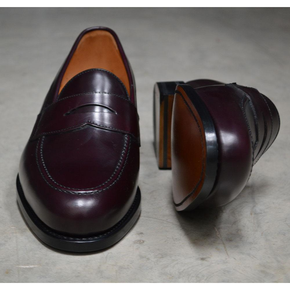 A burgundy high-shine leather penny loafer by Berwick 1707, displaying the classic round toe shape and the brand's distinctive penny slot detail.