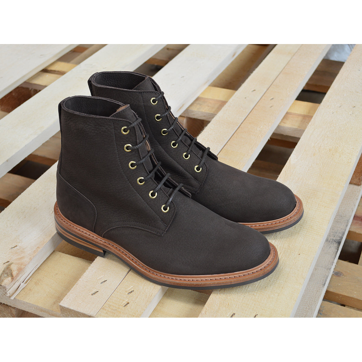 A dark brown Trickers Bernwood service boot made of Hydro Nubuck with a Dainite sole, featuring brass eyelets and a cream Barbour welt.