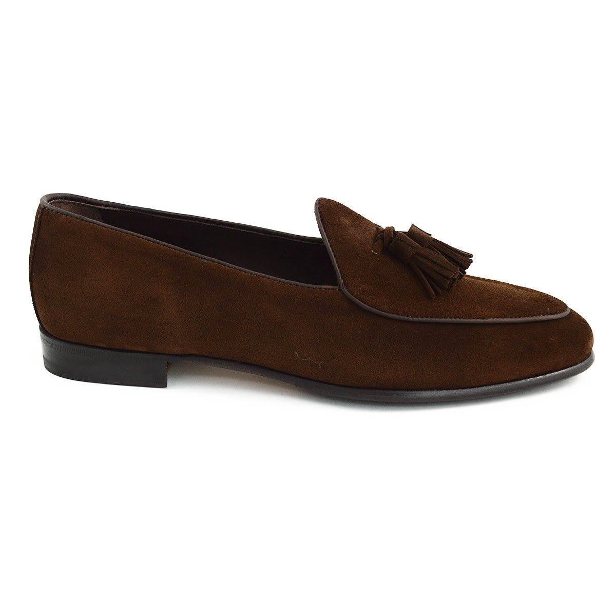 A dark brown suede tassel loafer with a Vegano Moka leather trim, displaying an almond-shaped toe and a fine ridged rubber sole.