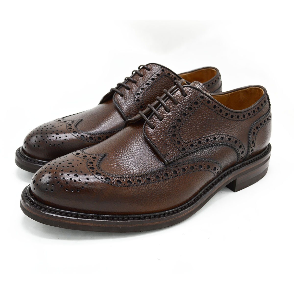 A Berwick 1707 brown brogue derby shoe with a round toe shape and lace-up closure. It features a grainy texture and brogue detailing & Dainite soles