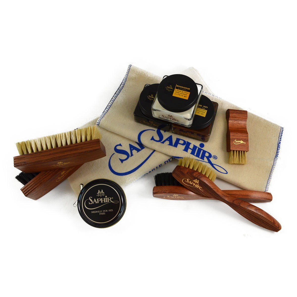 An assortment of shoe care products from Saphir Medaille D'Or including polishing cloths, brushes, cream polishes in black and medium brown, a shoe bag and a neutral wax polish.