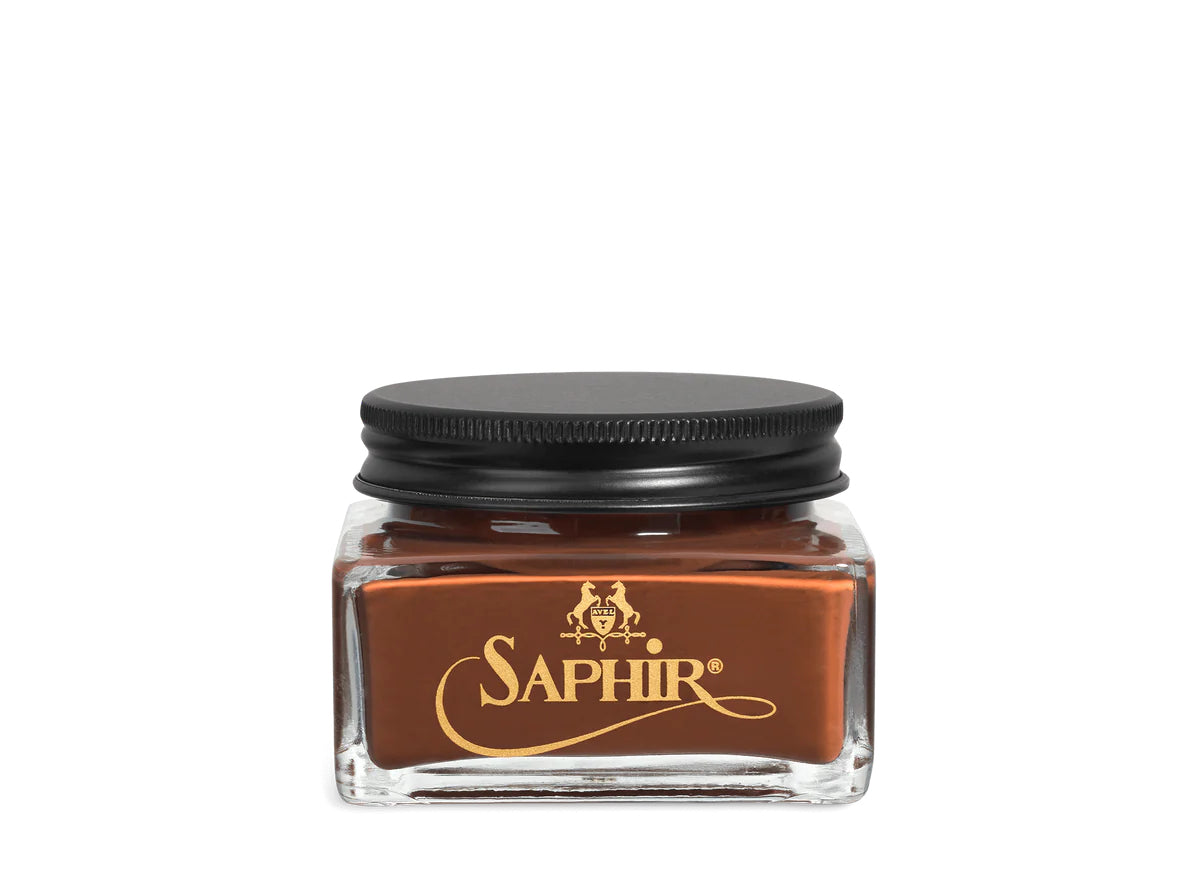 A glass jar with a black lid labeled 'SAPHIR' containing cream shoe polish.