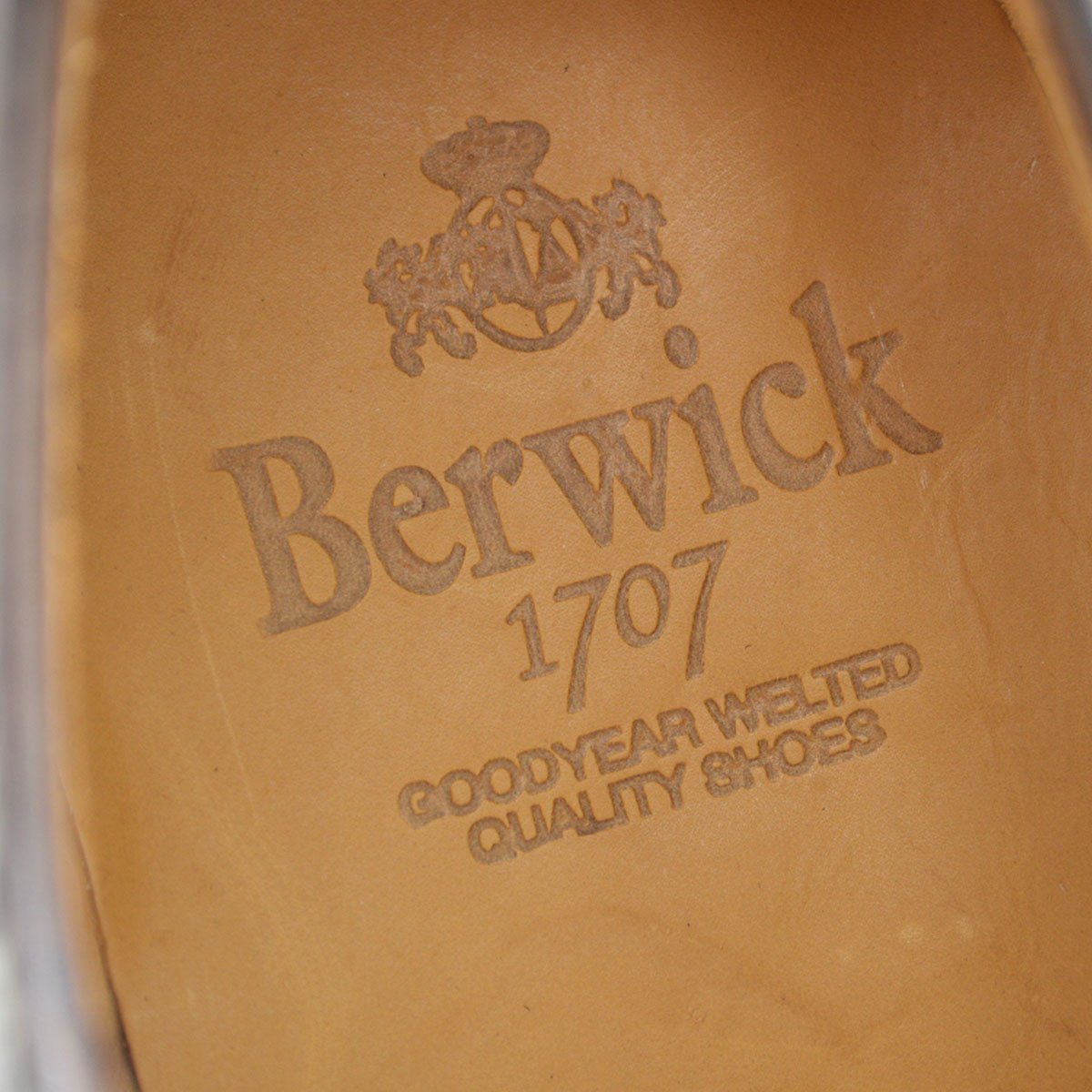 A Berwick 1707 brown brogue derby shoe with a round toe shape and lace-up closure. It features a grainy texture and brogue detailing & Dainite soles