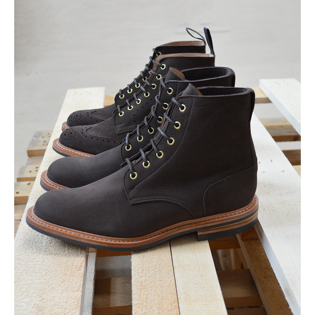 A dark brown Trickers Bernwood service boot made of Hydro Nubuck with a Dainite sole, featuring brass eyelets and a cream Barbour welt.