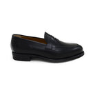 A black calf leather penny loafer with a Dainite rubber sole, showing a classic round toe shape and the iconic penny slot detail.