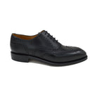 A Berwick 1707 black Oxford brogue shoe with brogue detailing and a lace-up closure. The shoe is made of smooth leather and appears to be sturdy and durable.
