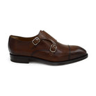 A brown calf leather double monk shoe with two buckle straps, on a white background.