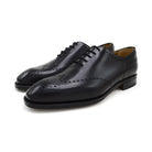 A black wholecut Oxford brogue shoe with a brogue pattern on the upper, a lace-up closure, and a goodyear welted leather sole.